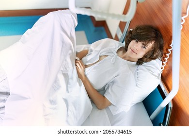 Portrait Of A Young Teenager Lying In A Hospital Bed In A Ward.  Boy Preparing For Surgery. Child Smiling At The Camera.  Urgent Hospitalization And Fast Recovery.