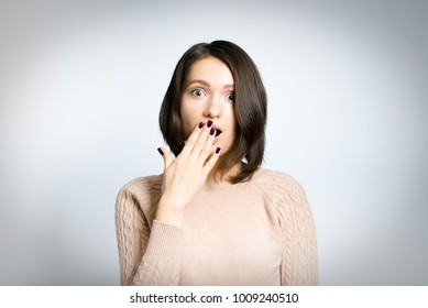 Portrait Of A Young Tender Woman Is Scared, In A Pink Sweater, Isolated Against A Background, Studio Photo