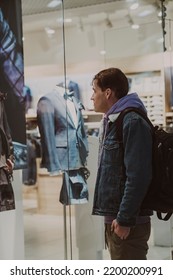 Portrait Of Young Thoughtful Man Considering Showcase In Shopping Center. Concept Of Shopping, Dream, Desire