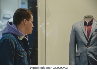 Portrait Of Young Thoughtful Man Considering Showcase In Shopping Center. Concept Of Shopping, Dream, Desire