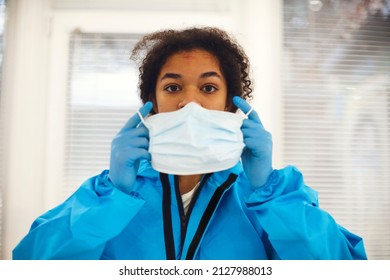 Portrait Of Young Tired African American Medical Worker Or Nurse In Protective Gear Taking Off Face Mask And Looking At Camera With Frustrated Expression. Healthcare Workers During COVID-19 Pandemic