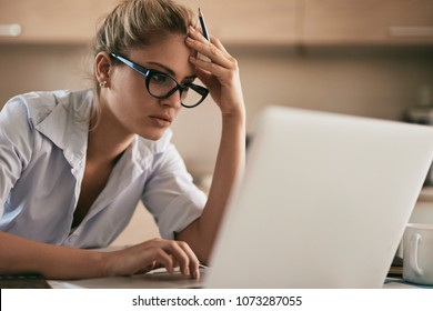 Portrait of a young tired businesswoman using laptop and working on some reports from home. - Powered by Shutterstock