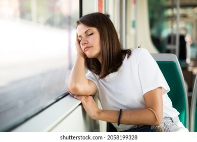 Portrait of young tired woman traveling in modern streetcar and sleeping