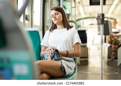 Portrait Of Young Tired Woman Traveling In Modern Streetcar And Sleeping