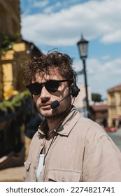 portrait of young tour guide in sunglasses and headset looking at camera on blurred Andrews descent in Kyiv - Shutterstock ID 2274821741