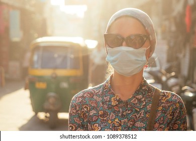 Portrait Of A Young Tourist Woman Wearing Sunglasses And A Mask On The Background Of A Street With Cars And People. The Concept Of Tourism, Health And Safety In The Asian And Indian Countries