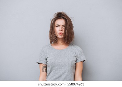 Portrait Of A Young Upset Girl In T-shirt Looking At Camera Isolated On A Gray Background