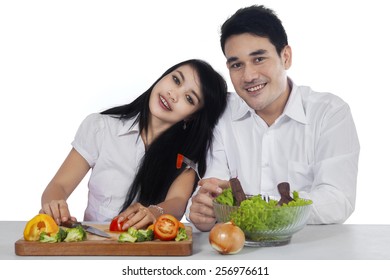 Portrait of young vegetarian couple with fresh salad, smiling at the camera isolated on white