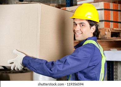 Portrait Of A Young Warehouse Worker Lifting Cardboard Box