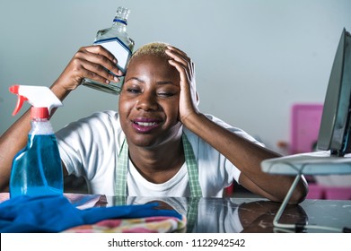 Portrait Of Young Wasted And Drunk Alcoholic Black Afro American Housewife Drinking Alcohol Bottle At Home Kitchen Feeling Desperate And Sad In Alcohol Addiction And Abuse Problem