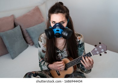 Porträt einer jungen weißen Frau in antibakterieller Maske und floralem Kleid spielen ihre Ukulele auf dem Bett sitzen zu Hause durch die Isolation von COVID-19.