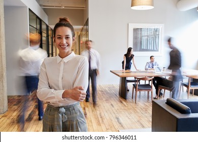 Portrait young white woman in busy modern workplace