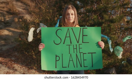 Portrait young woman activist holding encouraging green poster Save the Planet standing at landfill site with garbage nature environmental community earth eco environment outdoor recycle trash waste