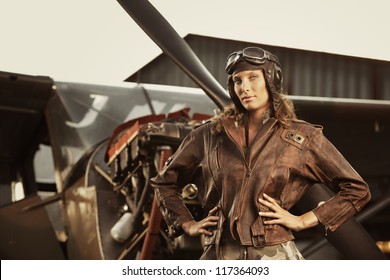 Portrait of young woman airplane pilot. Airplane on the background
