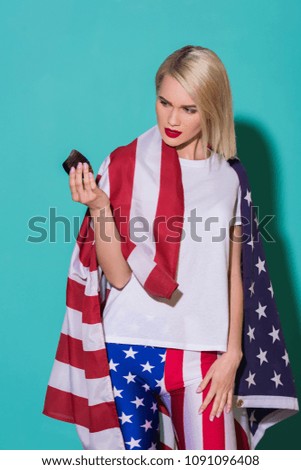 portrait of young woman with american flag and cupcake on blue backdrop, celebrating 4th july concept