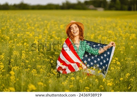 Portrait young woman with American national flag, enjoying sunset at field. 4th of July. Independence Day. Patriotic holiday.