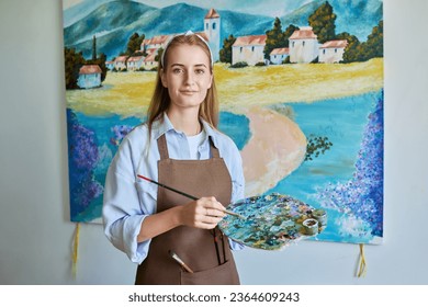 Portrait of young woman artist painting picture on canvas - Shutterstock ID 2364609243