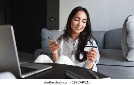 Portrait Of Young Woman, Asian Girl Shopping Online, Paying Bills With Credit Card, Laptop And Smartphone, Enter Card Number In Mobile Phone App To Purchase Smth In Internet Store