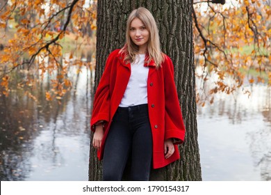 Portrait of young woman in autumn park near big old oak and lake 
