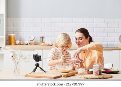 Portrait Of Young Woman Baking Cupcakes With Cute Little Boy Helping Mom In Kitchen And Recording Cooking Video