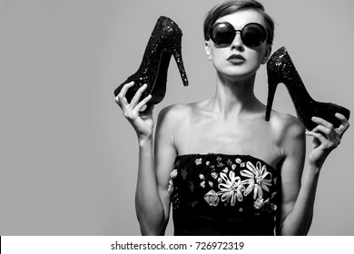 Portrait of young woman in black dress with heels for Black Friday over grey background, grain added - Powered by Shutterstock