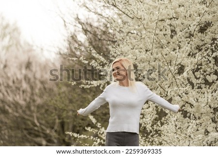 Portrait of a young woman in a blooming orchard. Blonde woman