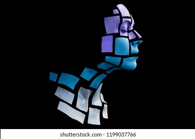 Portrait of a young woman with bold glowing makeup posing in the studio. Shape of cold colored squares on woman face. Isolated on black background.