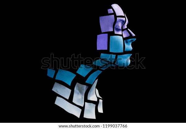 Portrait of a young woman with bold glowing\
makeup posing in the studio. Shape of cold colored squares on woman\
face. Isolated on black\
background.