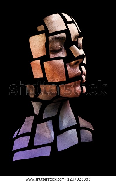 Portrait of a young woman with bold glowing\
makeup posing in the studio. Shape of colored squares on woman\
face. Isolated on black\
background.