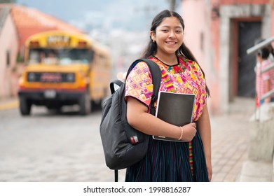Portrait of a young woman with books and backpack at a bus stop.