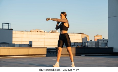 Portrait of young woman in boxing gloves doing exercises outdoors. Beautiful sports girl stretching before boxing exercising on punch bag at sports ground. Warming up for fighting - Powered by Shutterstock