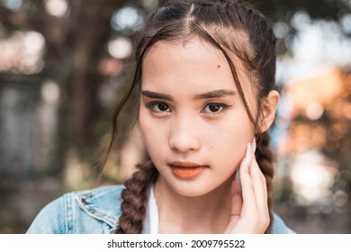 Portrait Of A Young Woman With Braided Ponytail Hair Casually Posing Outdoors.