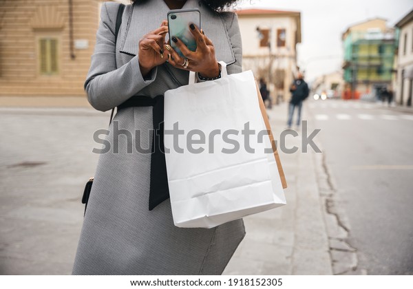 Portrait of a\
young woman at bus stop while checking notifications on smartphone\
- Millennial are looking for a car sharing service during the\
Coronavirus Covid-19\
pandemic