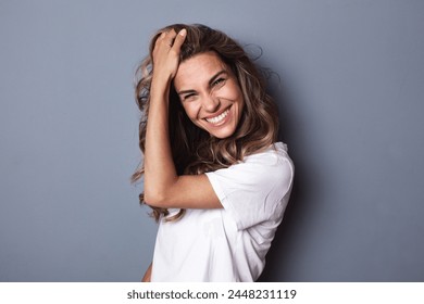 Portrait of young woman casual portrait in positive look, wide smile beautiful model posing in studio on gray background.  - Powered by Shutterstock