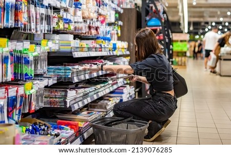 Portrait of young woman choosing school stationery in supermarket. shopping