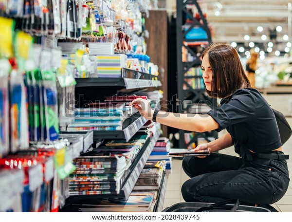 Portrait of young woman choosing school\
stationery in\
supermarket.