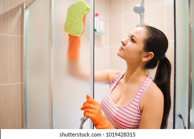 Portrait Of Young Woman Cleaning Shower Door