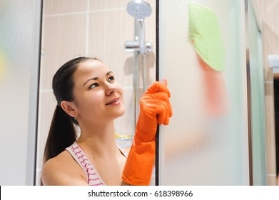 Portrait Of Young Woman Cleaning Shower Door