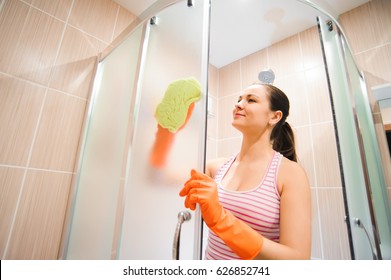 Portrait Of Young Woman Cleaning Shower Door