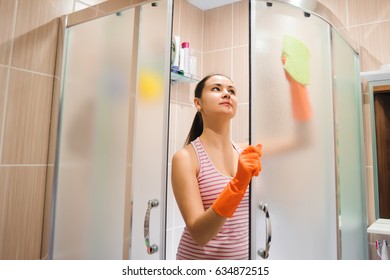 Portrait Of Young Woman Cleaning Shower Door