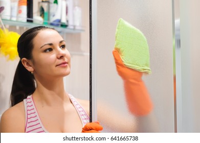 Portrait Of Young Woman Cleaning Shower Door