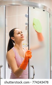 Portrait Of Young Woman Cleaning Shower Door