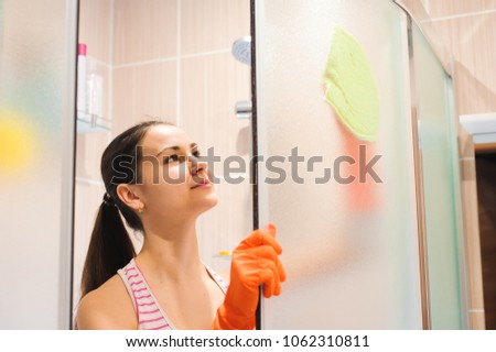 portrait of young woman cleaning shower door