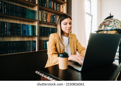 Portrait Of Young Woman College Student Studying With Laptop, Preparing For Test Exam, Writing Essay Doing Homework In The Library.