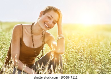 Portrait of young woman crouching in field of grass