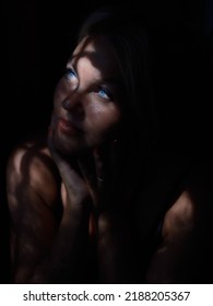 Portrait Of A Young Woman In The Dark With Partial Natural Light Through The Window