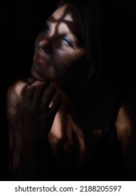 Portrait Of A Young Woman In The Dark With Partial Natural Light Through The Window