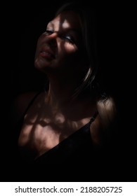 Portrait Of A Young Woman In The Dark With Partial Natural Light Through The Window