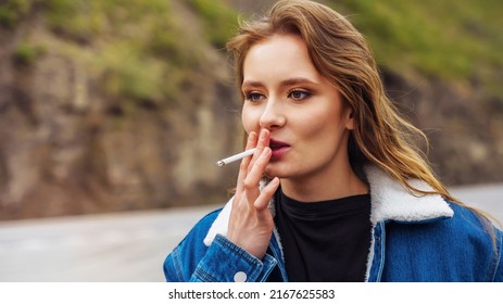 Portrait Of A Young Woman In A Denim Jacket Smoking A Cigarette By The Road.