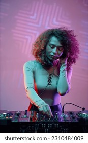 Portrait of young woman DJ making music tracks at nightclub in neon light - Shutterstock ID 2310484009